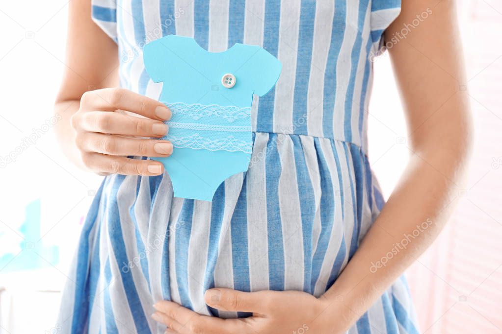 Pregnant woman holding card near belly, closeup