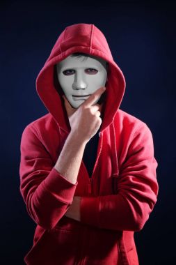 Masked hacker wearing hoodie in darkness