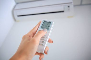 Genç kadın kapalı Klima uzaktan kumanda işaret