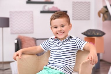 Evde koltukta oturan sevimli küçük çocuk