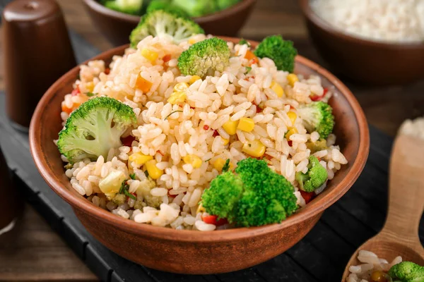 Delicious rice pilaf with broccoli in bowl on wooden table
