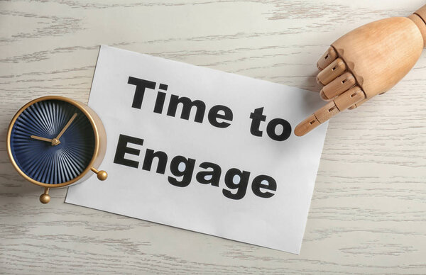 Часы и манекен стороны указывая на лист бумаги с фразой ВРЕМЯ ДЛЯ ДВИЖЕНИЯ на деревянном фоне
