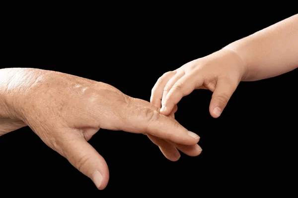 Hands of elderly man and baby on dark background