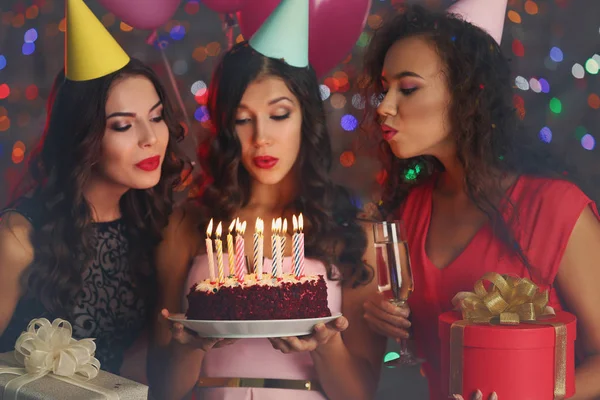 在生日蛋糕上吹蜡烛的美丽的年轻妇女在党 — 图库照片