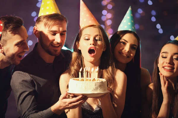 若い女性のパーティーでの誕生日ケーキのろうそくを吹き — ストック写真