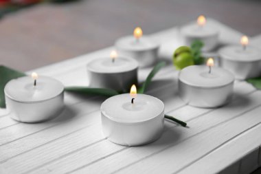 Beyaz ahşap tahta, closeup üzerinde yanan mumlar