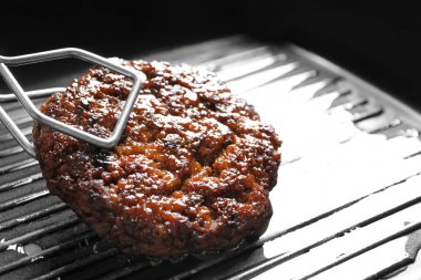 Burger patty ızgara yüzeyi, closeup koyarak maşa