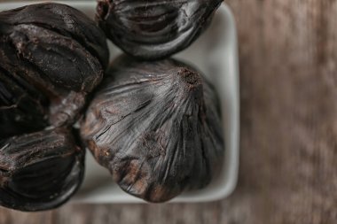 Siyah sarımsak (Allium sativum), bir kase portre