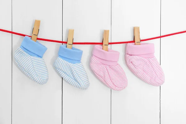 Baby booties on laundry line against wooden background