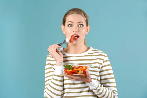 색상 배경에 신선한 샐러드를 먹는 젊은 아름 다운 여자 — 스톡 사진