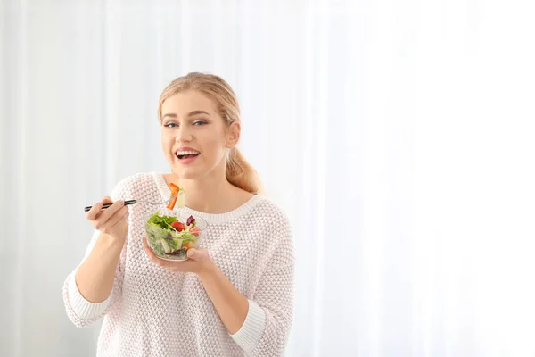 Młoda kobieta piękne jedzenie świeże sałatki, na jasnym tle — Zdjęcie stockowe