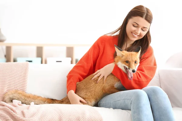 Young woman with pet fox indoors