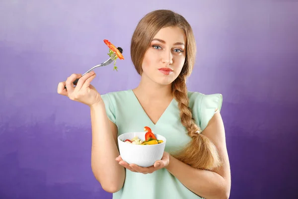 年轻美丽的妇女吃新鲜的沙拉在颜色背景 — 图库照片