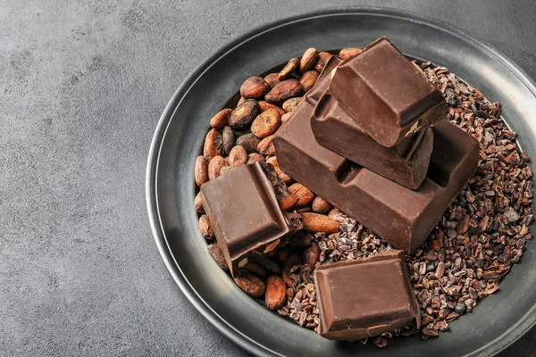 Plate with chocolate and cocoa products on table