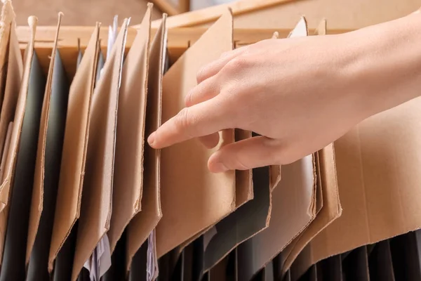 Woman searching for documents in archive, closeup