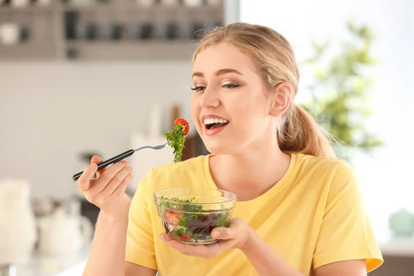 Giovane bella donna mangiare insalata fresca in cucina — Foto Stock