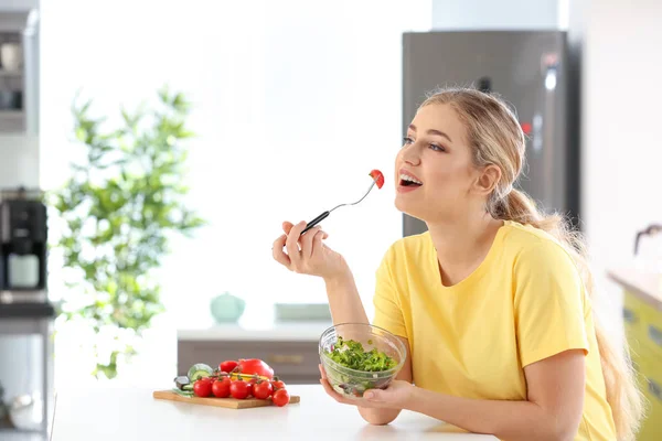 Joven hermosa mujer comiendo ensalada fresca en la cocina —  Fotos de Stock
