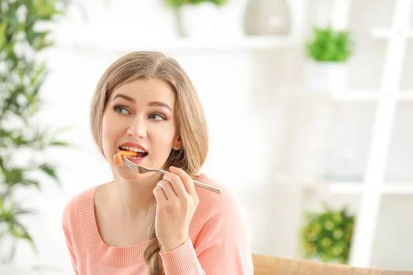 Giovane bella donna mangiare insalata fresca su sfondo sfocato — Foto Stock