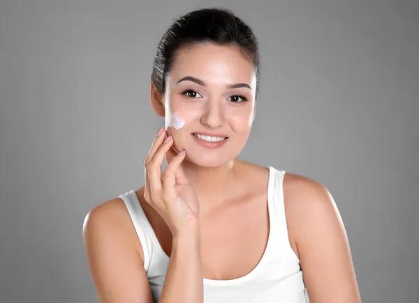 Attractive Young Woman Applying Face Cream Grey Background — Stock Photo, Image