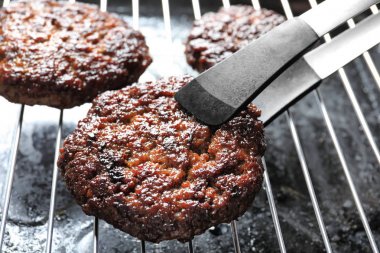 Burger patty ızgara, closeup koyarak maşa