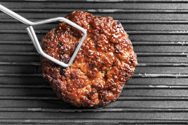 Burger patty ızgara yüzeyi, closeup koyarak maşa