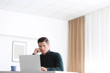 Masada kapalı dizüstü bilgisayar kullanan genç adam