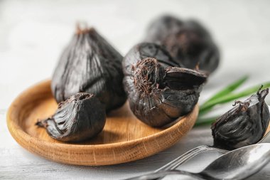 Ahşap masa üzerinde siyah sarımsak (Allium sativum) ile plaka