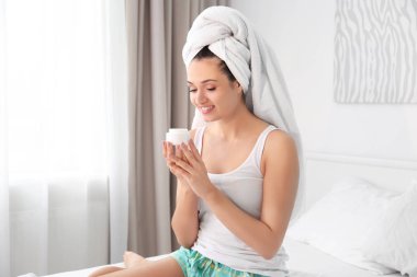 Çekici genç bir kadın evde yüz kremi sürüyor.