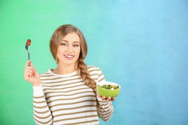 Renk arka plan üzerinde taze salata yemek genç güzel kadın