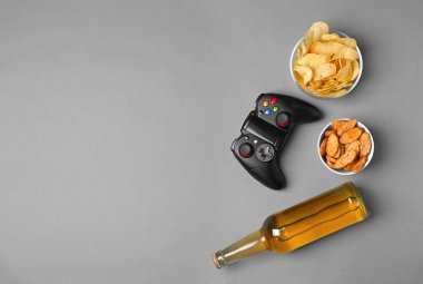 Video oyun denetleyicisi, bira ve gri arka plan üzerinde snack kompozisyonu
