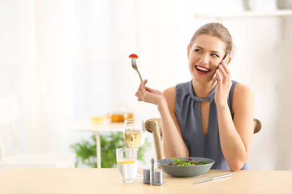Młoda kobieta piękne rozmowy na telefon podczas jedzenia świeże sałatki w domu — Zdjęcie stockowe