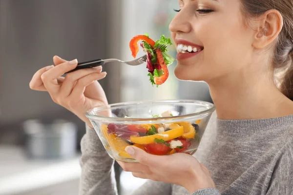 Giovane bella donna mangiare insalata fresca su sfondo sfocato — Foto Stock