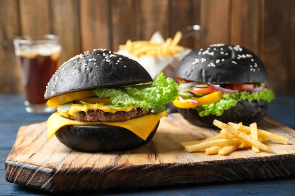 Holzbrett Mit Leckeren Schwarzen Burgern Und Pommes Auf Dem Tisch — Stockfoto