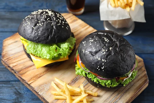 Holzbrett Mit Leckeren Schwarzen Burgern Und Pommes Auf Dem Tisch — Stockfoto