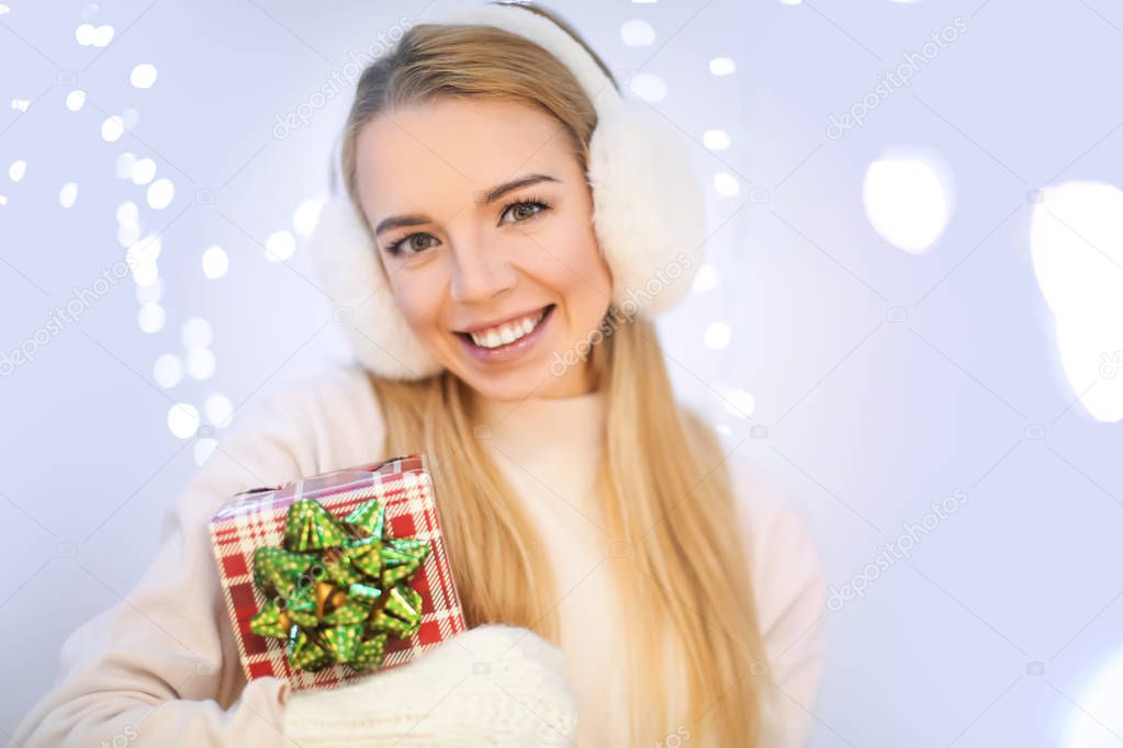 Happy woman with gift box against blurred lights