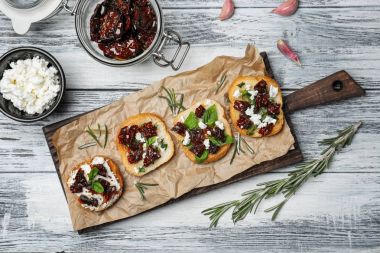 Ahşap masa, üstten görünüm üzerinde kurutulmuş domatesli lezzetli bruschettas