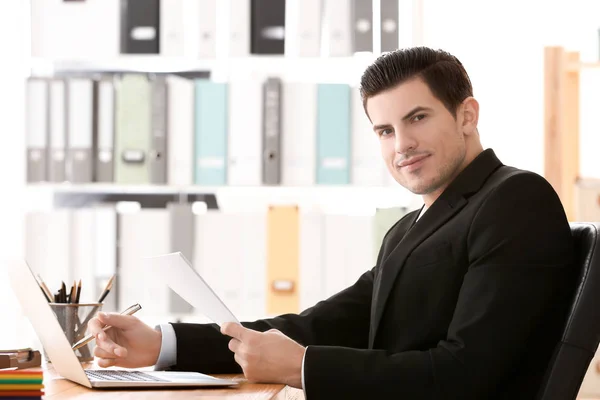 Young man working with laptop and documents in archive