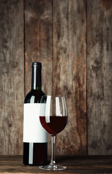 赤ワインと木製のテーブルで空白のラベルとボトルのガラス デザインのために模擬します — ストック写真