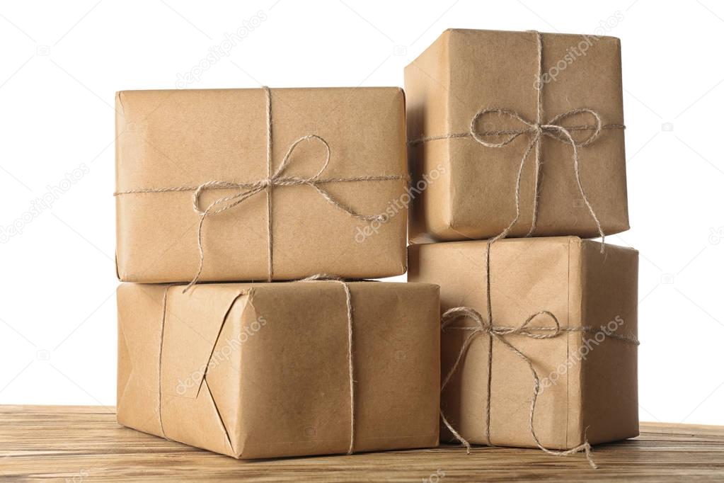 Parcel gift boxes on wooden table against white wall