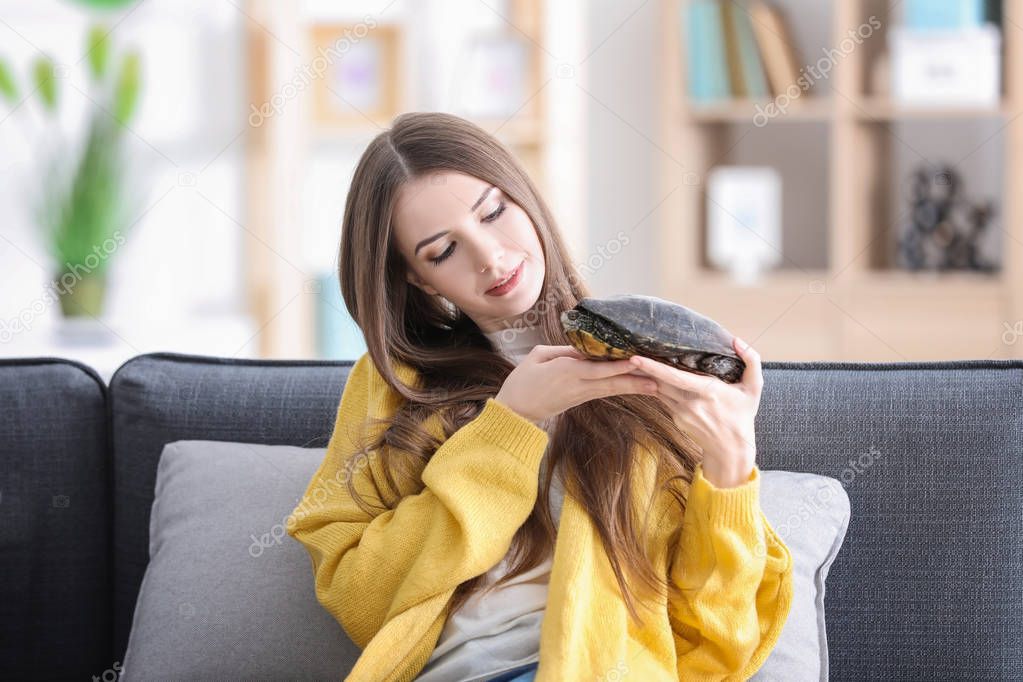 Beautiful young woman with pet turtle at home