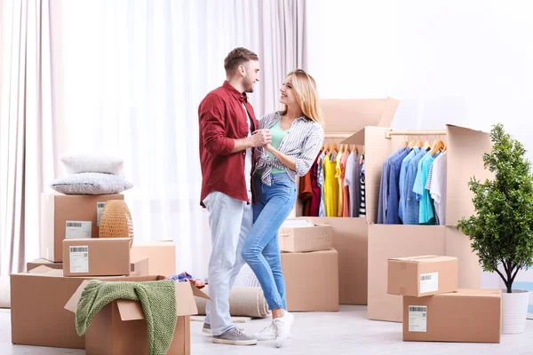 Young couple dancing near wardrobe boxes on moving day