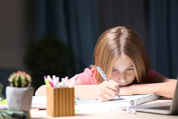Dospívající dívka dělat domácí úkoly u stolu v večer — Stock fotografie