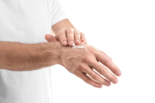 Человек наносит крем для рук на белом фоне, крупным планом — стоковое фото
