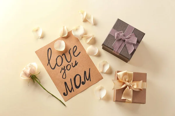 Tarjeta con palabras "Te amo mamá", rosa y cajas de regalo sobre fondo claro. Saludos para el día de la madre —  Fotos de Stock