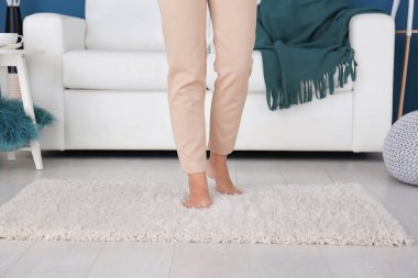 Evde yumuşak halı üzerinde yürüyen kadın