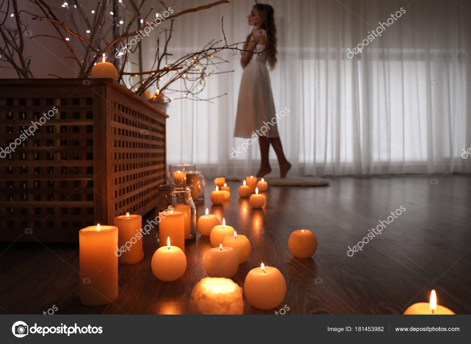 Young Woman Standing In Room With Burning Candles On Floor Stock