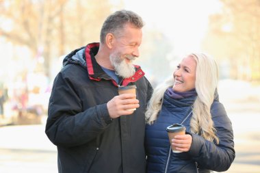 Mutlu olgun çift sokakta yürürken ve sonbahar gününde kahve içme