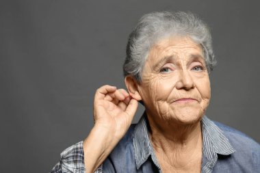 Yaşlı kadın ile gri arka plan üzerinde işitme sorunu