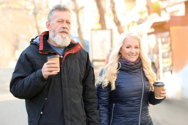 Mutlu olgun çift sokakta yürürken ve sonbahar gününde kahve içme