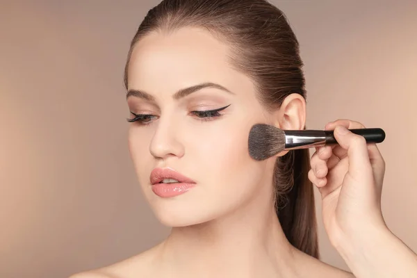 Professionell visage konstnären tillämpa makeup på kvinnans ansikte på färg bakgrunden — Stockfoto